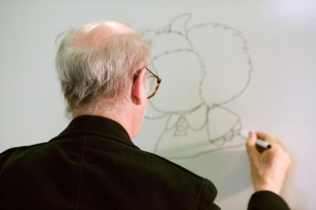 Retratos de Quino dibujando a Mafalda en una pizarra