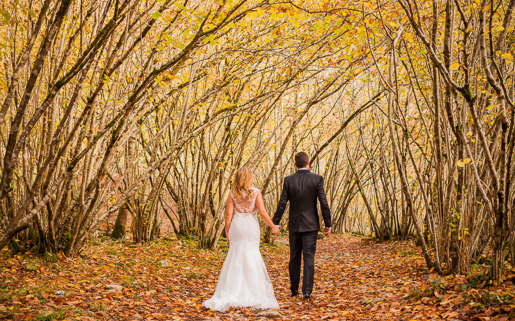 Pareja de novios en pos boda entre árboles otoño