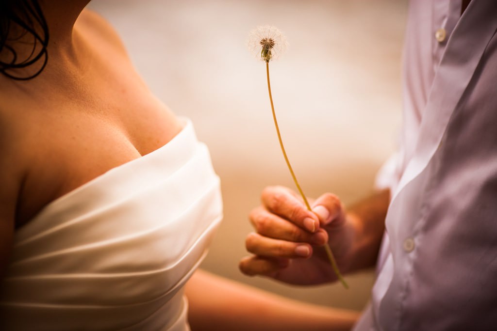 detalle de manos de novios con flor posboda